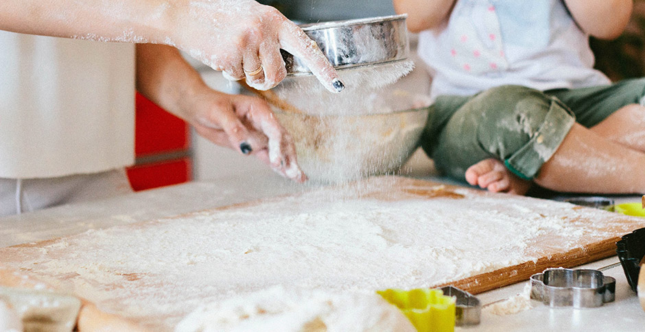 Parent and child sifting flour