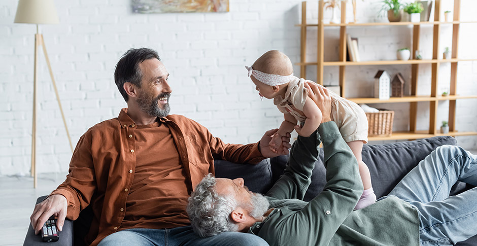 Cheerful same sex couple holding baby daughter 