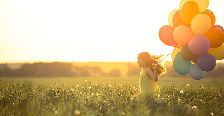 Young girl with bunch of coloured balloons