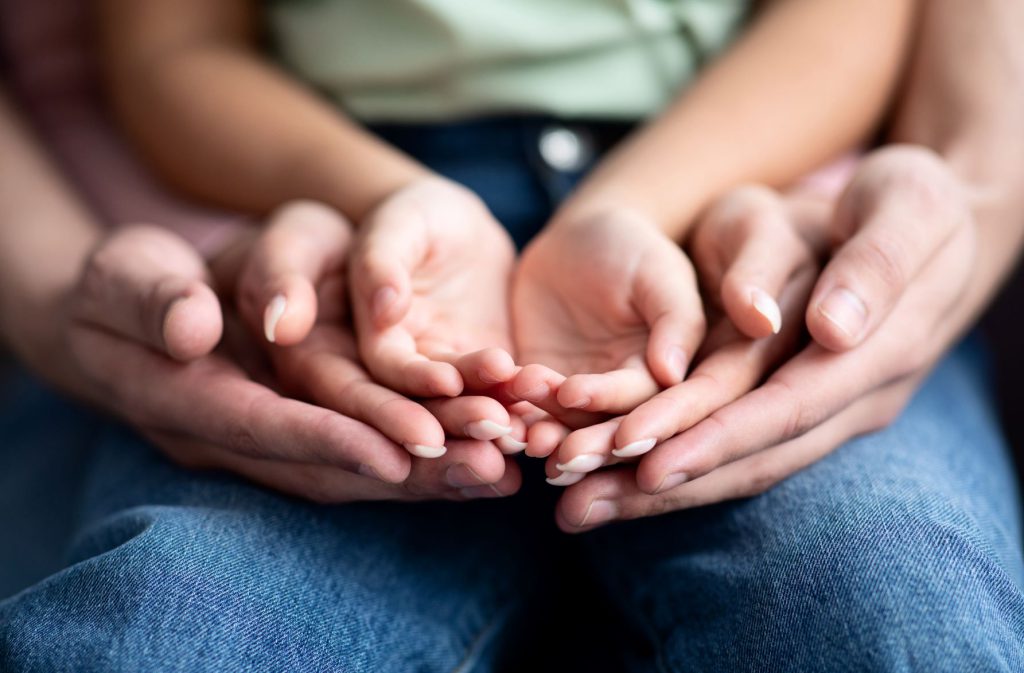 Parents and child placing their hands on top of each other