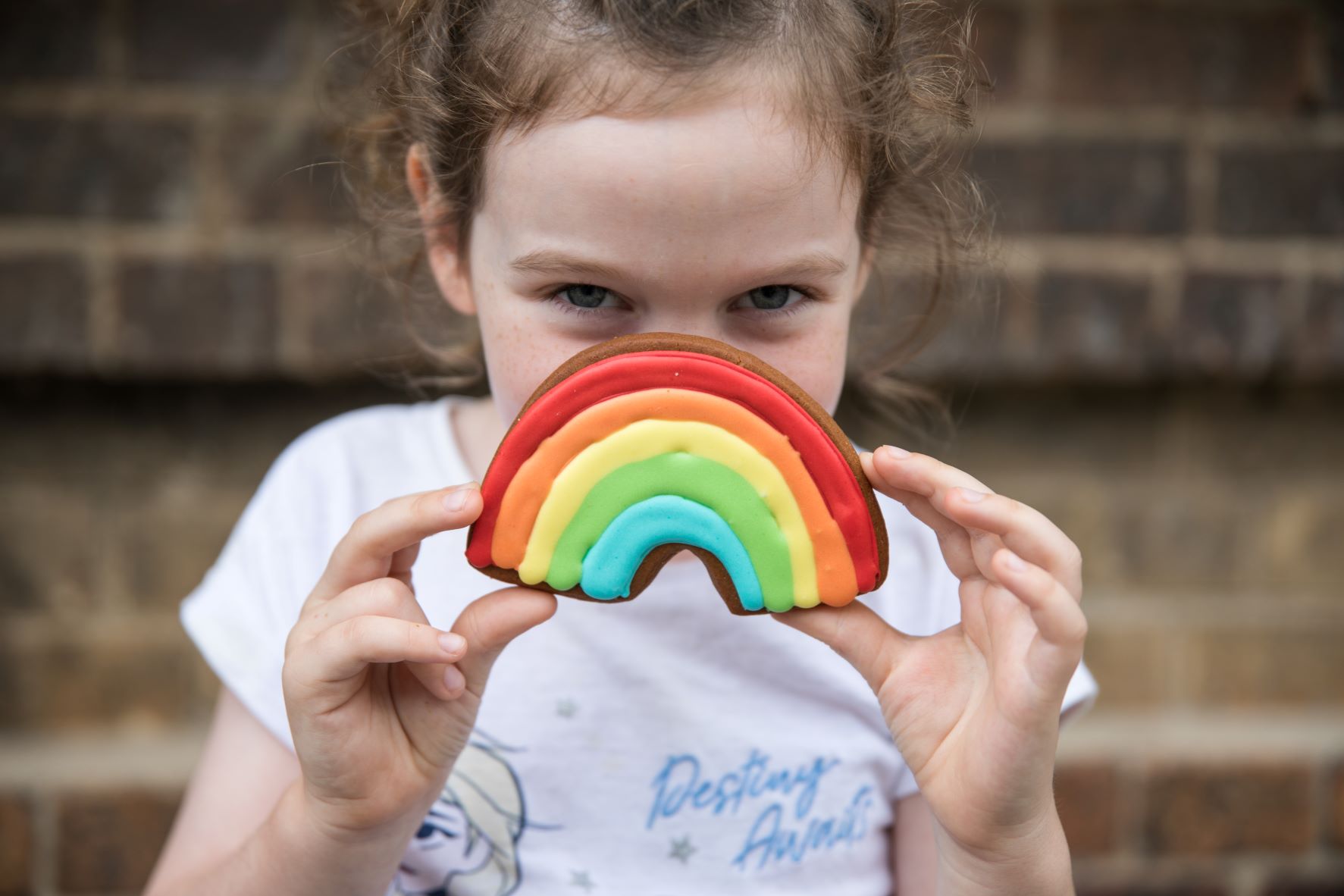 Young girl with a rainbow biscuit